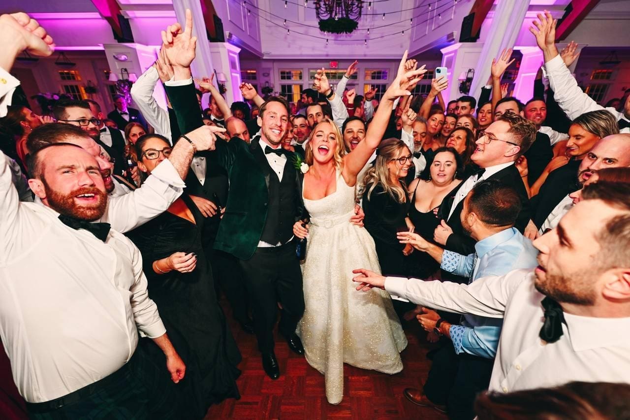 Wedding guests celebrating on a packed dance floor with professional DJ lighting at a North Carolina wedding reception.